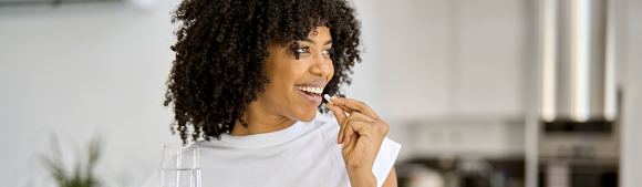 Woman consuming a dietary supplement in a bright home environment