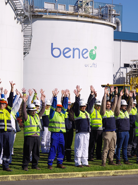 Empleados de BENEO con equipos de seguridad levantan las manos frente a un tanque industrial en la planta