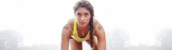 Female sprinter in starting position on an outdoor running track, ready to race