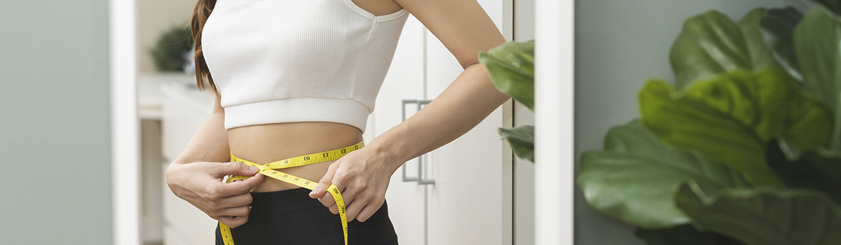Woman measuring waist with tape to track weight goals supporting healthy blood sugar management