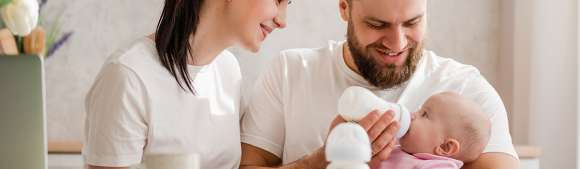 Parents feeding baby with formula containing prebiotic fiber supporting early digestive wellness