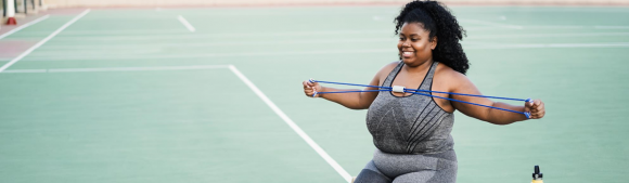 Woman exercising with resistance band outdoors, supporting active lifestyle and overall wellness